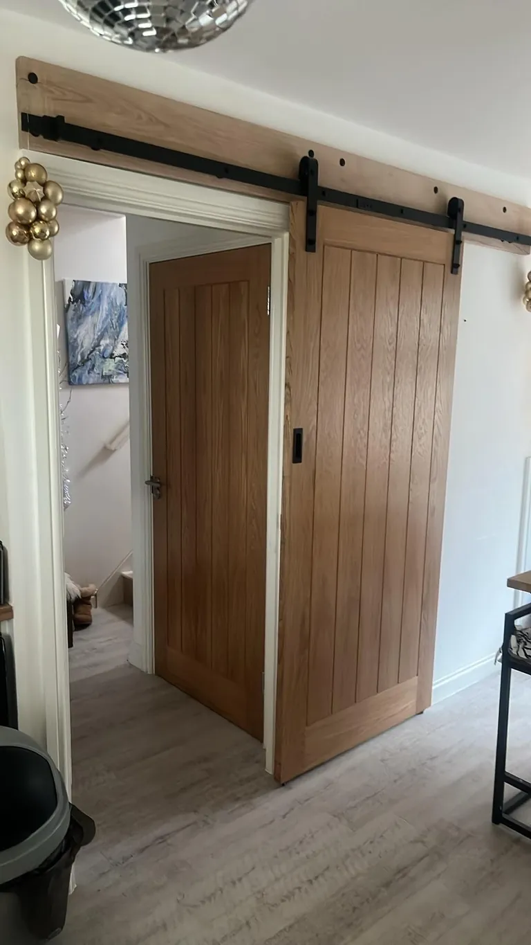 Oak barn door on a black track beside an oak internal door