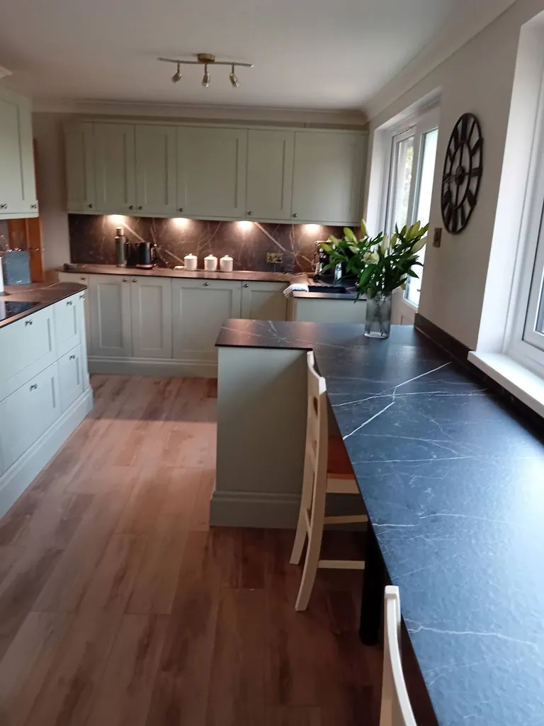 Sage shaker kitchen with black worktops and wood-effect flooring
