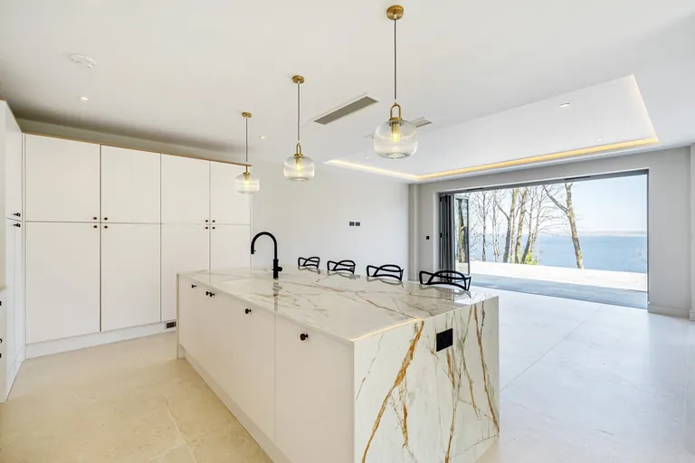 White kitchen island with a marble-effect worktop and a sea view