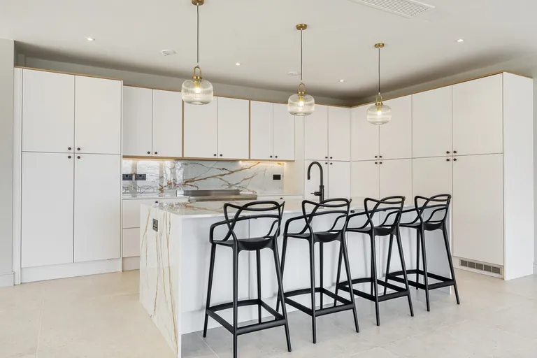 White handleless kitchen with a marble-effect island and bar seating