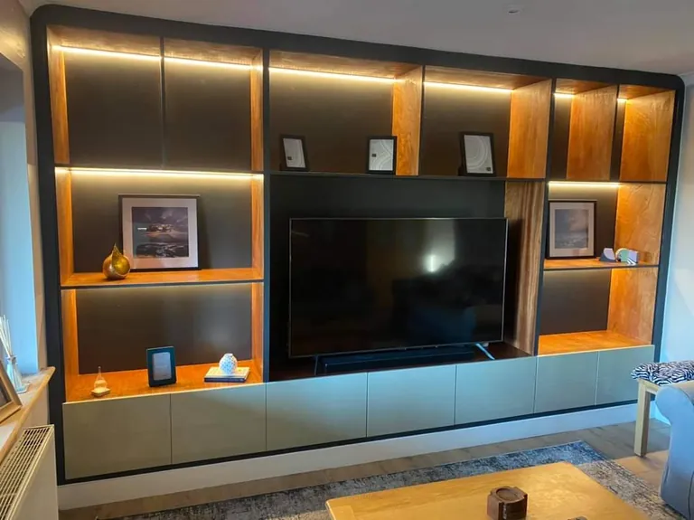 Media wall with lit oak shelving and a TV recess